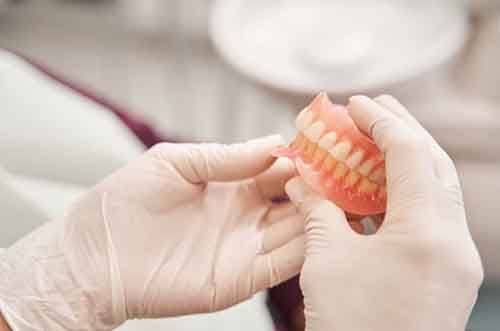 a person holding a pair of dentures