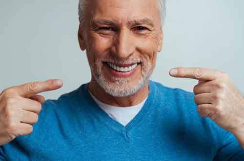 a man smiling and pointing at his dentures